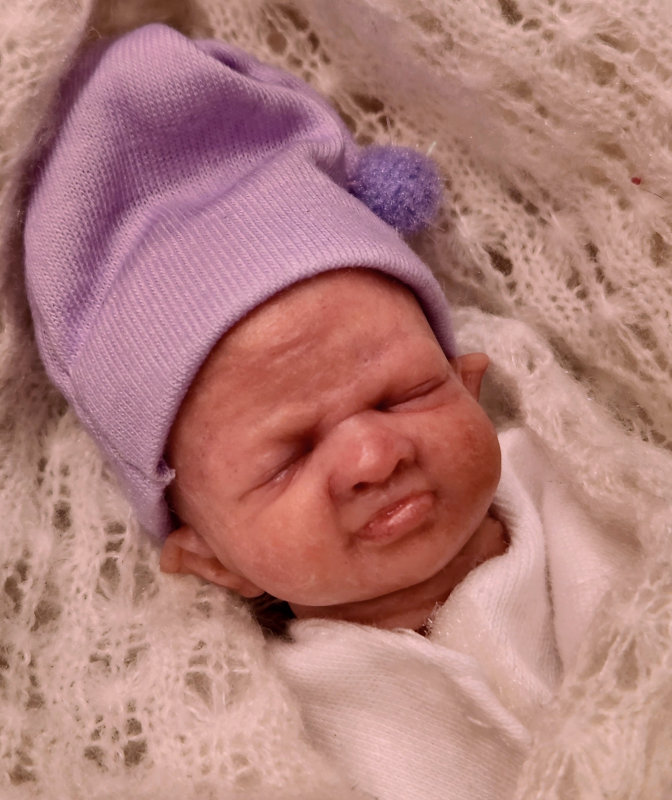 Closeup of the face of a baby doll with an expressive face.